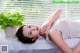 A woman laying on a bed next to a potted plant.