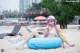 A woman in a bikini sitting on an inflatable ring on the beach.