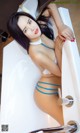 A woman in a blue bikini sitting in a bathtub.