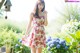 A woman in a red and white dress standing in a garden.