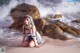 A woman sitting on a beach next to the ocean.