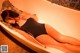 A woman in a black bathing suit laying in a bathtub.