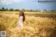 A woman in a pink dress standing in a field of wheat.