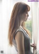 A woman standing by a window looking out the window.