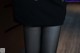 A close up of a person wearing black tights and a skirt.